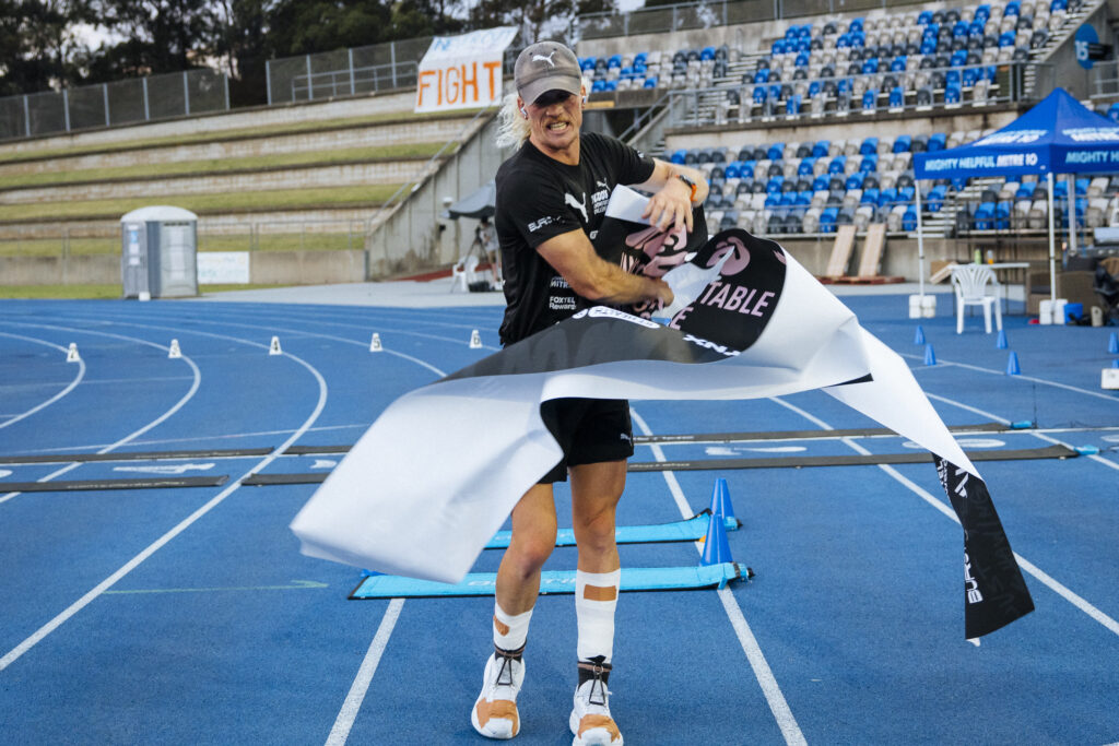 Nedd Brockmann crossing the finish line at Sydney Olympic Park after running 1000 miles for Nedd's Uncomfortable Challenge 2024